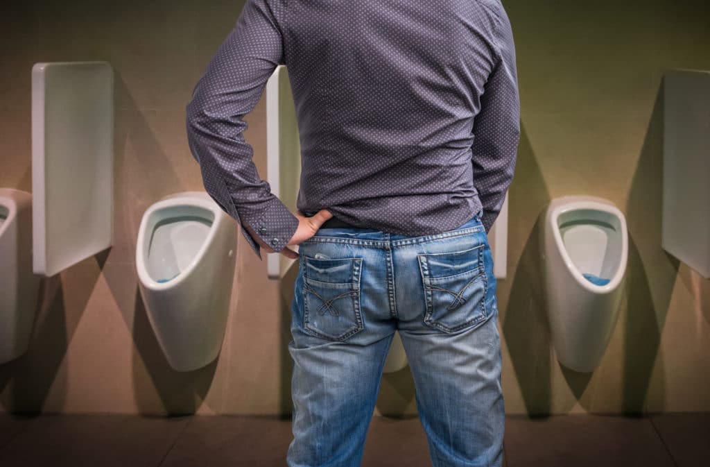 Svag urinstråle (mand tisser på offentligt toilet)